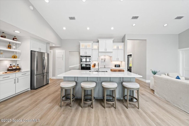 kitchen with decorative backsplash, a large island with sink, and stainless steel appliances