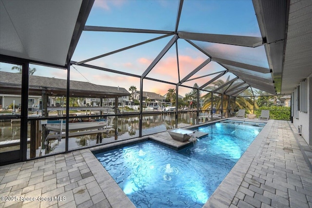 pool at dusk with a lanai, pool water feature, a dock, and a water view