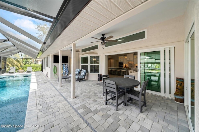 view of patio with ceiling fan and glass enclosure