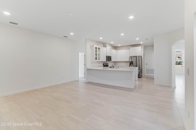 kitchen with kitchen peninsula, light tile patterned flooring, white cabinetry, and stainless steel appliances