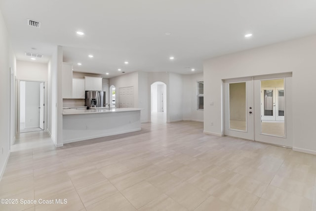 unfurnished living room with french doors, sink, and light tile patterned flooring