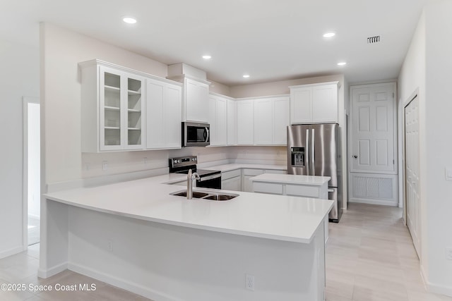 kitchen featuring kitchen peninsula, appliances with stainless steel finishes, white cabinets, and sink