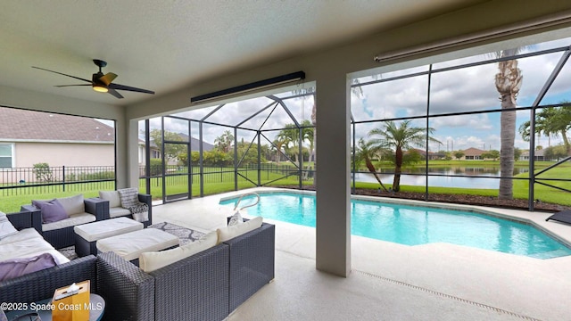 view of swimming pool featuring a lawn, glass enclosure, outdoor lounge area, a water view, and a patio area