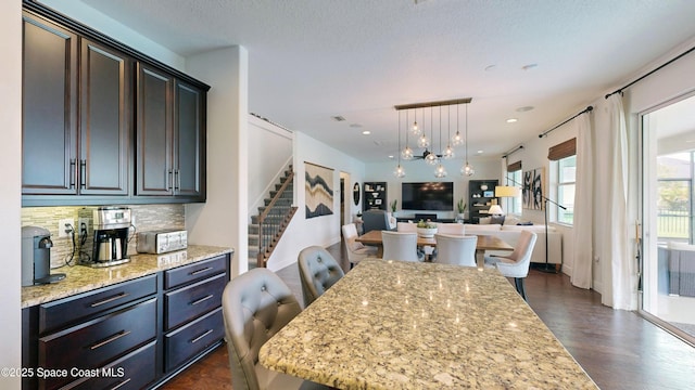 kitchen featuring light stone countertops, a center island, tasteful backsplash, pendant lighting, and a breakfast bar area