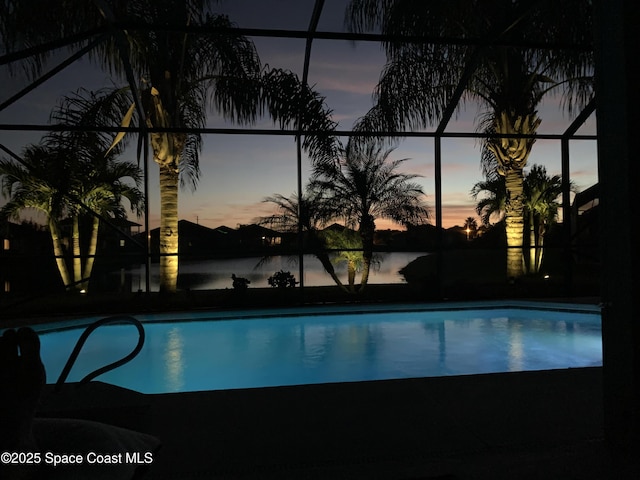 pool at dusk with a lanai and a water view