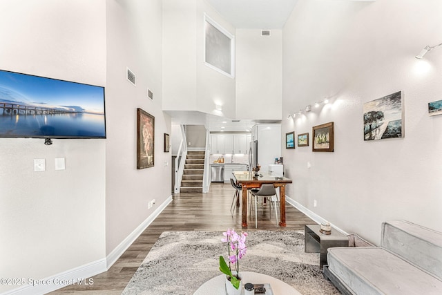 living room with hardwood / wood-style floors and a towering ceiling