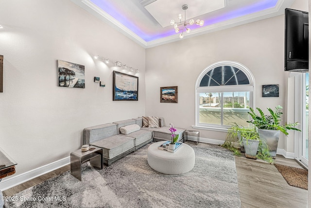 living room with hardwood / wood-style floors, a notable chandelier, and a tray ceiling