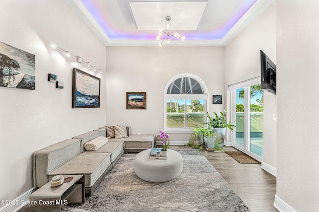 living room featuring dark hardwood / wood-style flooring, a raised ceiling, and an inviting chandelier