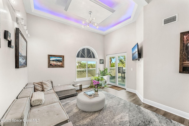 living room featuring hardwood / wood-style flooring, a raised ceiling, and a chandelier