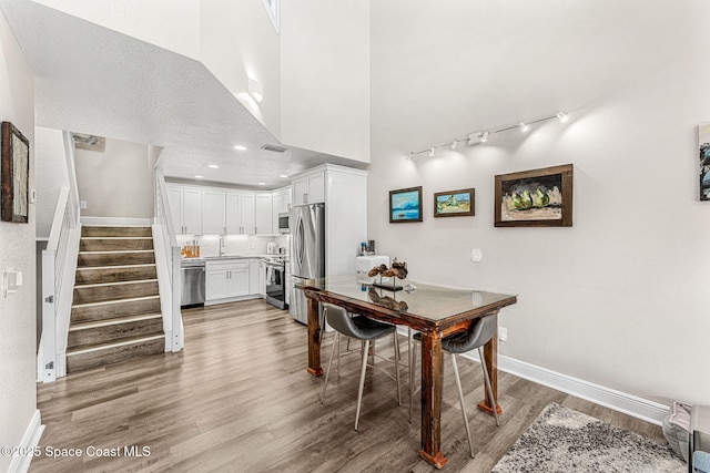 dining room with light hardwood / wood-style flooring and a towering ceiling