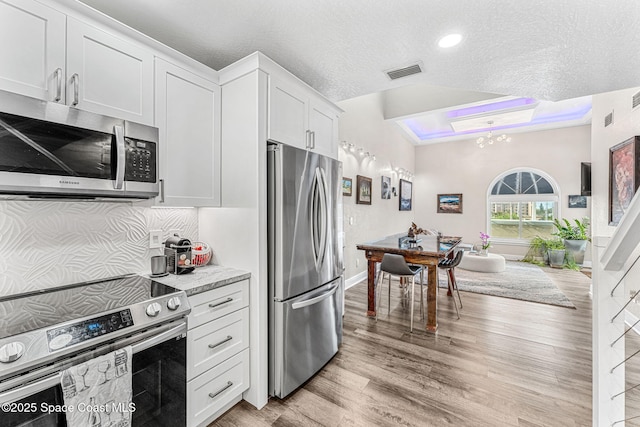 kitchen featuring white cabinetry, light hardwood / wood-style flooring, a textured ceiling, lofted ceiling, and appliances with stainless steel finishes