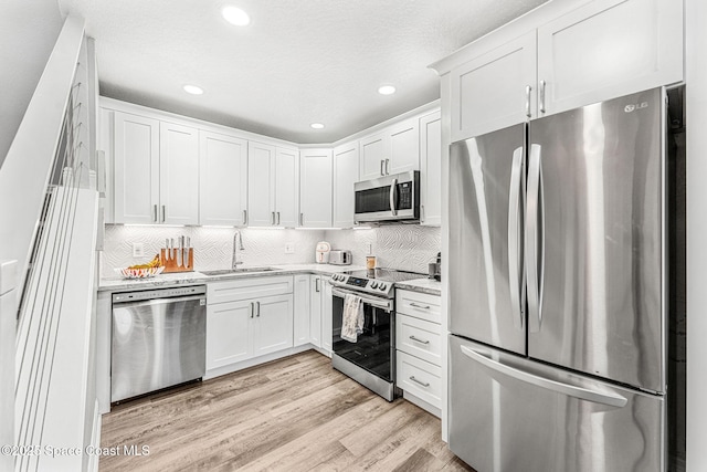 kitchen featuring white cabinets, stainless steel appliances, light hardwood / wood-style floors, and sink