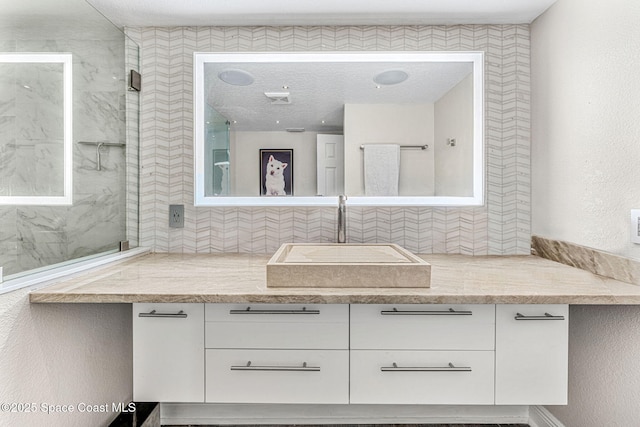 bathroom with tiled shower and vanity