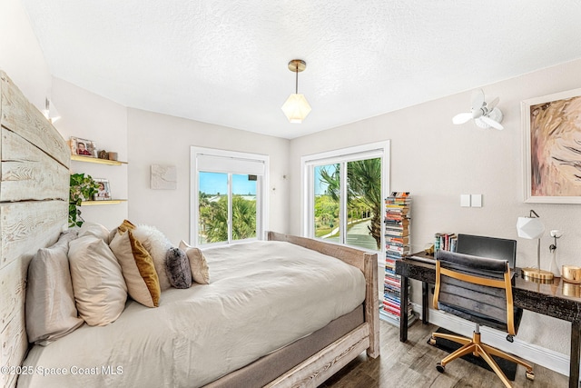 bedroom featuring a textured ceiling, access to exterior, and dark wood-type flooring