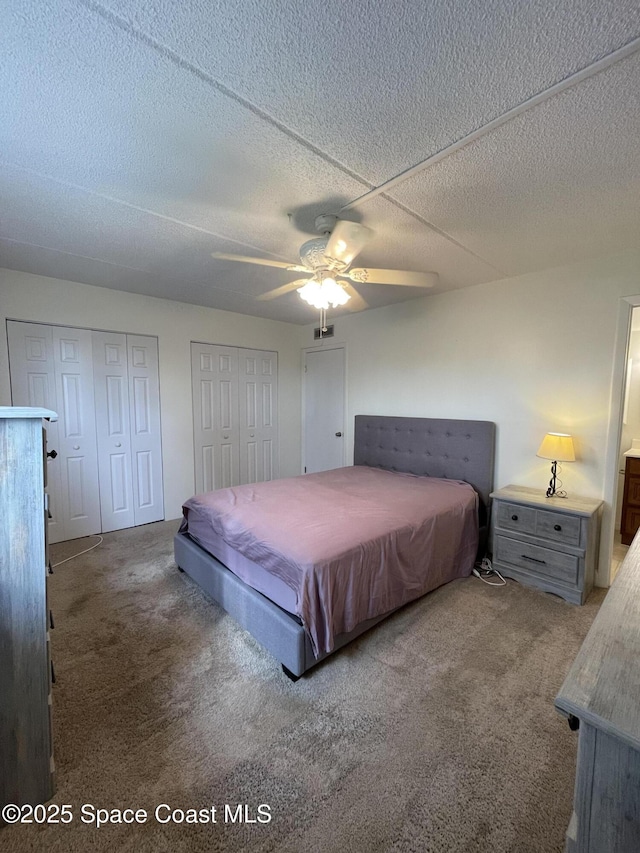 carpeted bedroom featuring ceiling fan and a textured ceiling