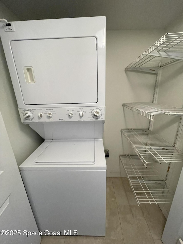 laundry room featuring stacked washing maching and dryer and tile patterned flooring