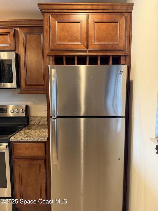 kitchen featuring appliances with stainless steel finishes and light stone counters