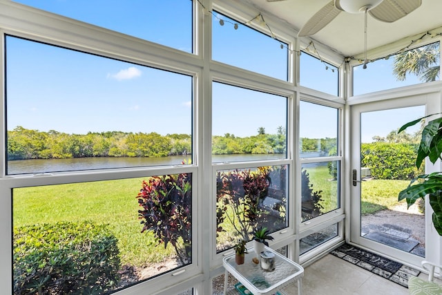 unfurnished sunroom featuring a water view, ceiling fan, and a healthy amount of sunlight