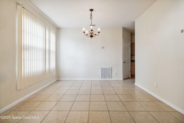 empty room featuring an inviting chandelier, light tile patterned floors, and plenty of natural light