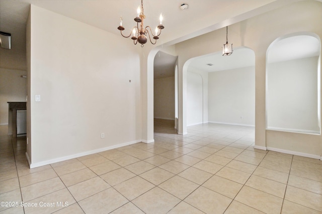 tiled spare room featuring an inviting chandelier