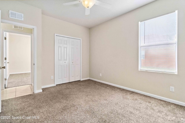 unfurnished bedroom featuring ceiling fan, a closet, and carpet flooring