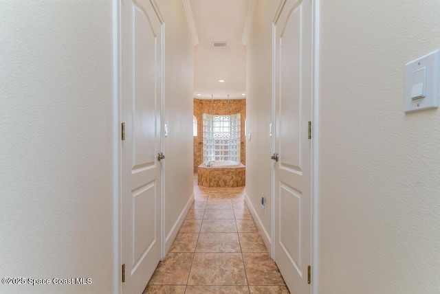 hallway featuring light tile patterned floors and ornamental molding