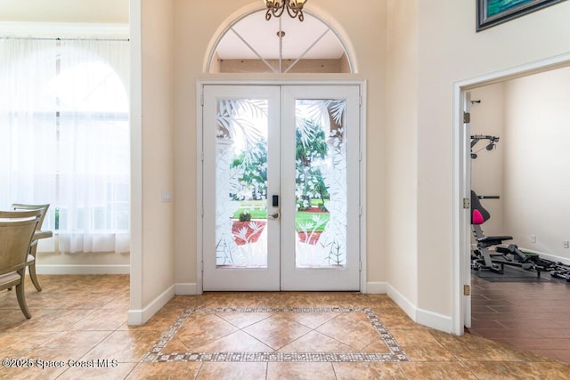 foyer with tile patterned flooring, a notable chandelier, french doors, and a healthy amount of sunlight