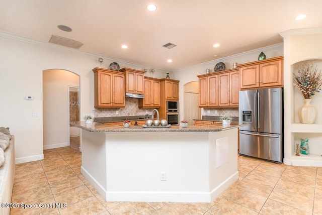 kitchen featuring stainless steel appliances, dark stone countertops, tasteful backsplash, and a kitchen island with sink