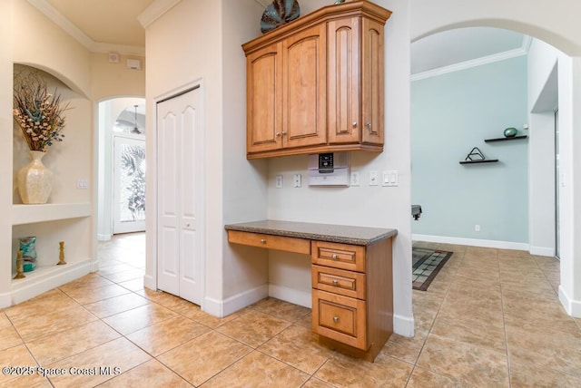 office space with built in desk, light tile patterned floors, and ornamental molding