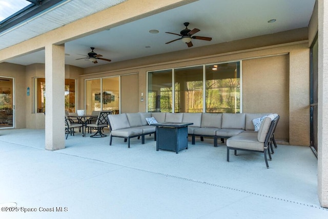 view of patio / terrace featuring ceiling fan and an outdoor living space with a fire pit