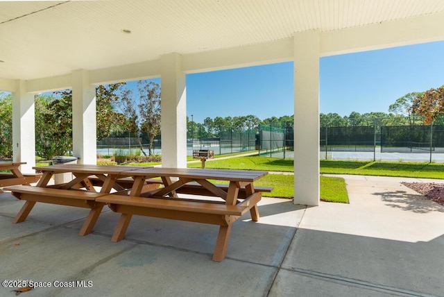 view of patio with a water view and tennis court