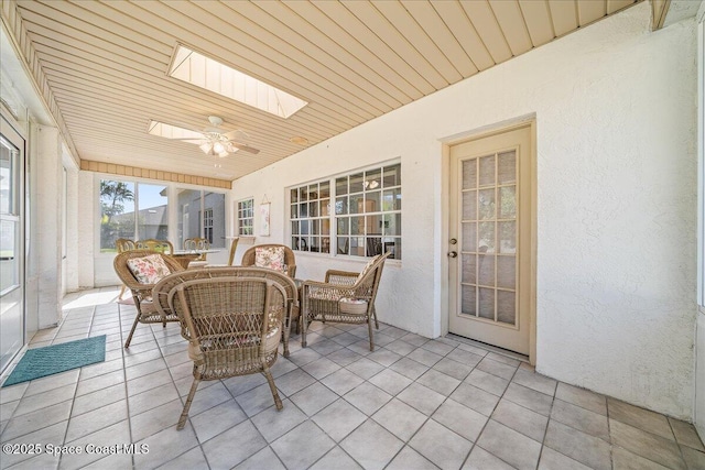 sunroom / solarium with wooden ceiling, ceiling fan, and a skylight