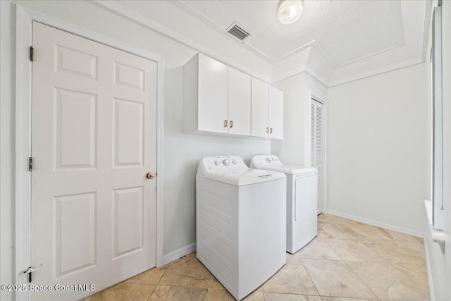 clothes washing area featuring cabinets, separate washer and dryer, light tile patterned floors, and a textured ceiling