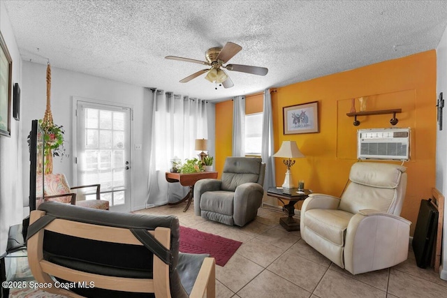 living area featuring a wall unit AC, ceiling fan, and light tile patterned flooring