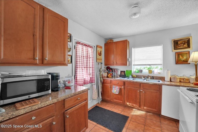 kitchen featuring light stone counters, white range, a textured ceiling, sink, and light tile patterned floors