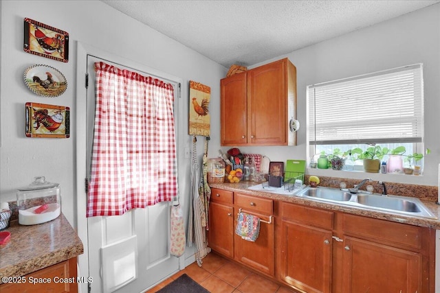 kitchen featuring light tile patterned flooring, a textured ceiling, and sink