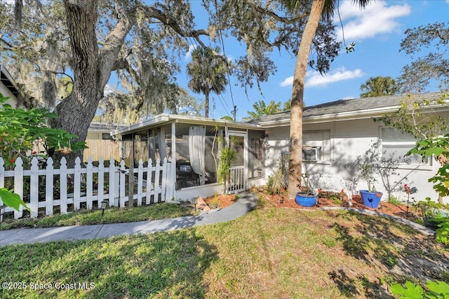 view of front of home featuring a sunroom and a front lawn