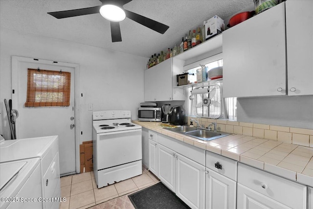 kitchen featuring white cabinetry, electric range, sink, tile counters, and independent washer and dryer