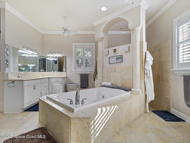 bathroom featuring decorative columns, vanity, ceiling fan, crown molding, and a relaxing tiled tub