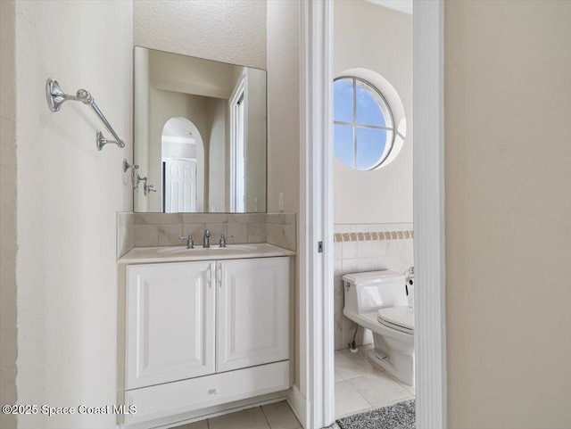 bathroom with tile patterned flooring, vanity, toilet, and tile walls