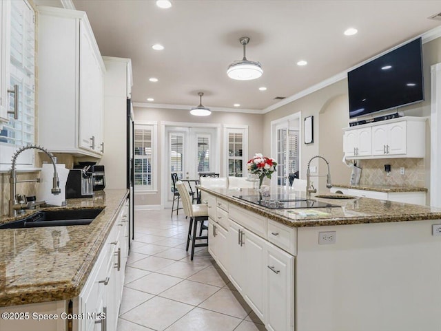 kitchen with white cabinets, light stone countertops, sink, and a kitchen island with sink