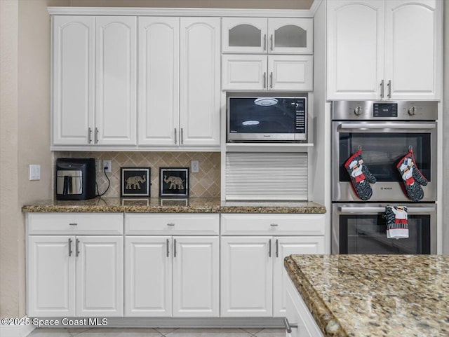 kitchen featuring dark stone counters, decorative backsplash, white cabinetry, and stainless steel appliances