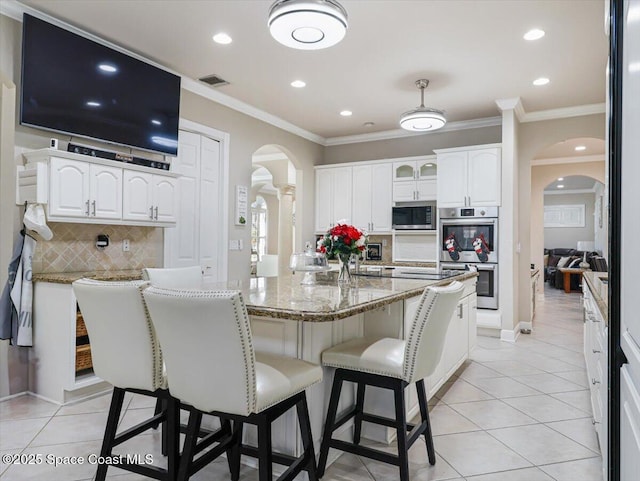 kitchen with light stone countertops, white cabinetry, stainless steel appliances, and tasteful backsplash