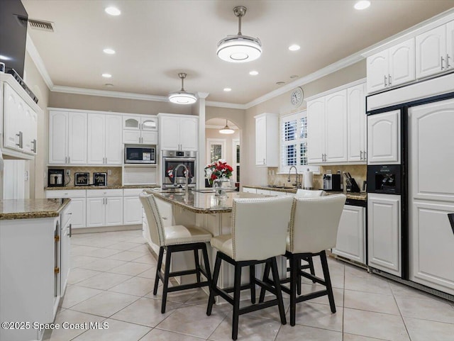 kitchen with white cabinetry, built in appliances, a kitchen island with sink, and stone countertops