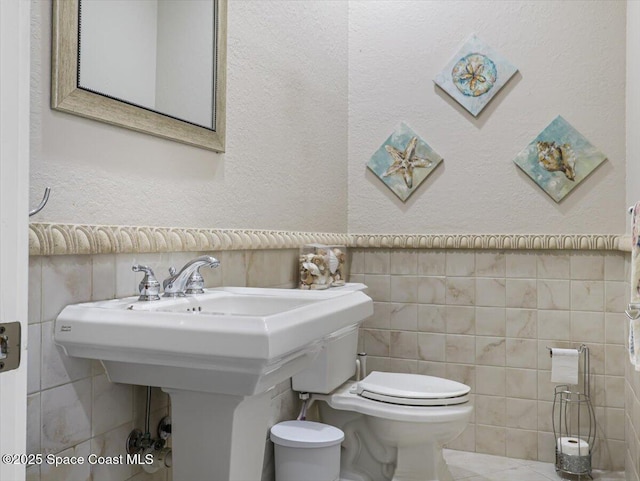 bathroom with tile walls and toilet