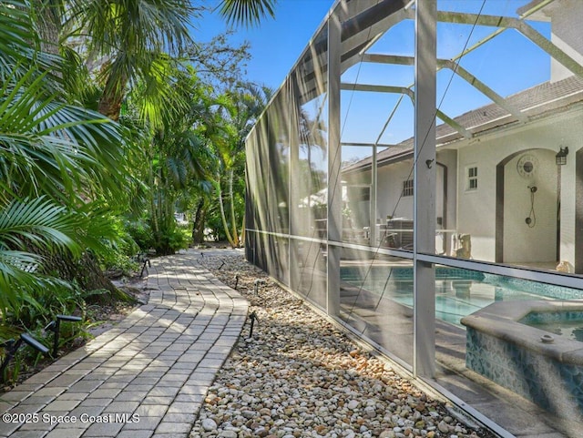 exterior space with glass enclosure and a swimming pool with hot tub