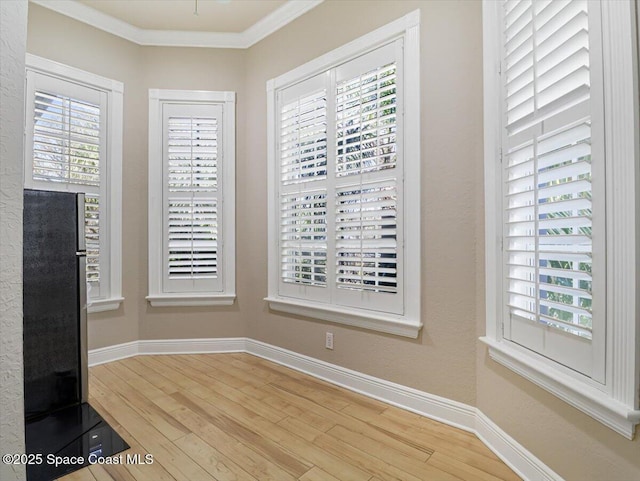 interior space with wood-type flooring, a healthy amount of sunlight, and ornamental molding