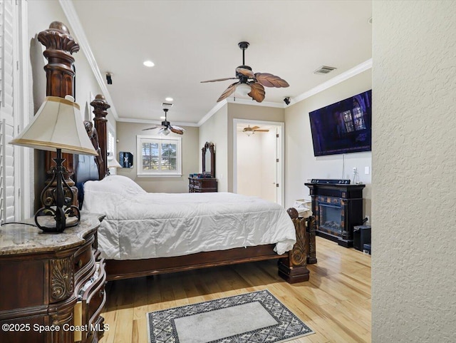 bedroom featuring ceiling fan, ornamental molding, and light hardwood / wood-style flooring