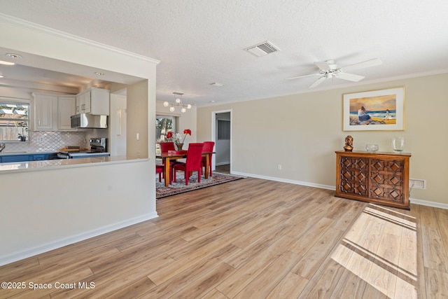 living room with ornamental molding, light wood finished floors, a textured ceiling, and visible vents