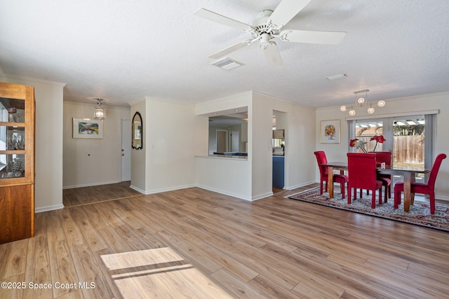 dining room with crown molding, a textured ceiling, visible vents, and wood finished floors